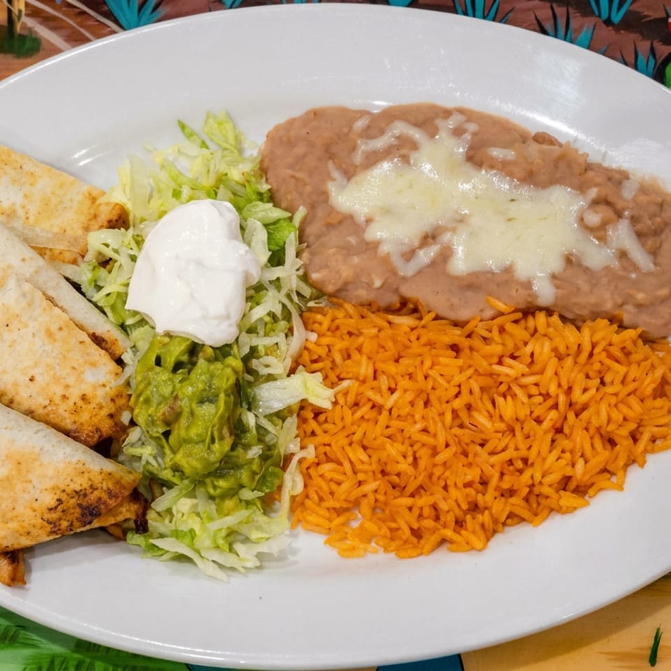 Mexican platter with quesadillas, refried beans topped with cheese, orange rice, lettuce, guacamole, and sour cream.